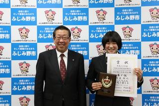 宮島 朝比選手が賞状と盾を手に持って、市長と一緒に笑顔で写っている写真