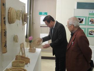 作品展示会の竹細工コーナーにて竹かごを手に取る市長の写真