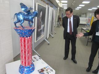 作品展示でスタッフに説明を受けながら青いペガサスの作品を鑑賞する市長の写真