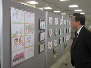 壁に貼られたたくさんの絵の展示を鑑賞する市長の写真
