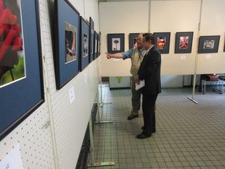 男性が展示写真を指をさして説明されているのを聞いている市長の写真