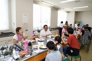 出来上がった料理を参加者達と笑顔で食べている市長の写真