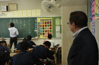 先生が黒板に字を書いている様子を教室の隅から見ている市長の写真