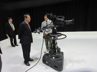 テレビカメラの傍に立っている市長と関係者が話をしている写真