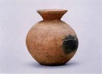 茶色の壺の表面に深緑色の模様がついた権現山古墳群2号墳から出土した底部穿孔壺形土器の写真