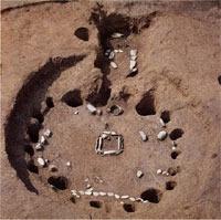 地面に柱を立てた跡の穴が円形に並び、中央に火をおこす場所の跡が残っている柄鏡住居跡の写真