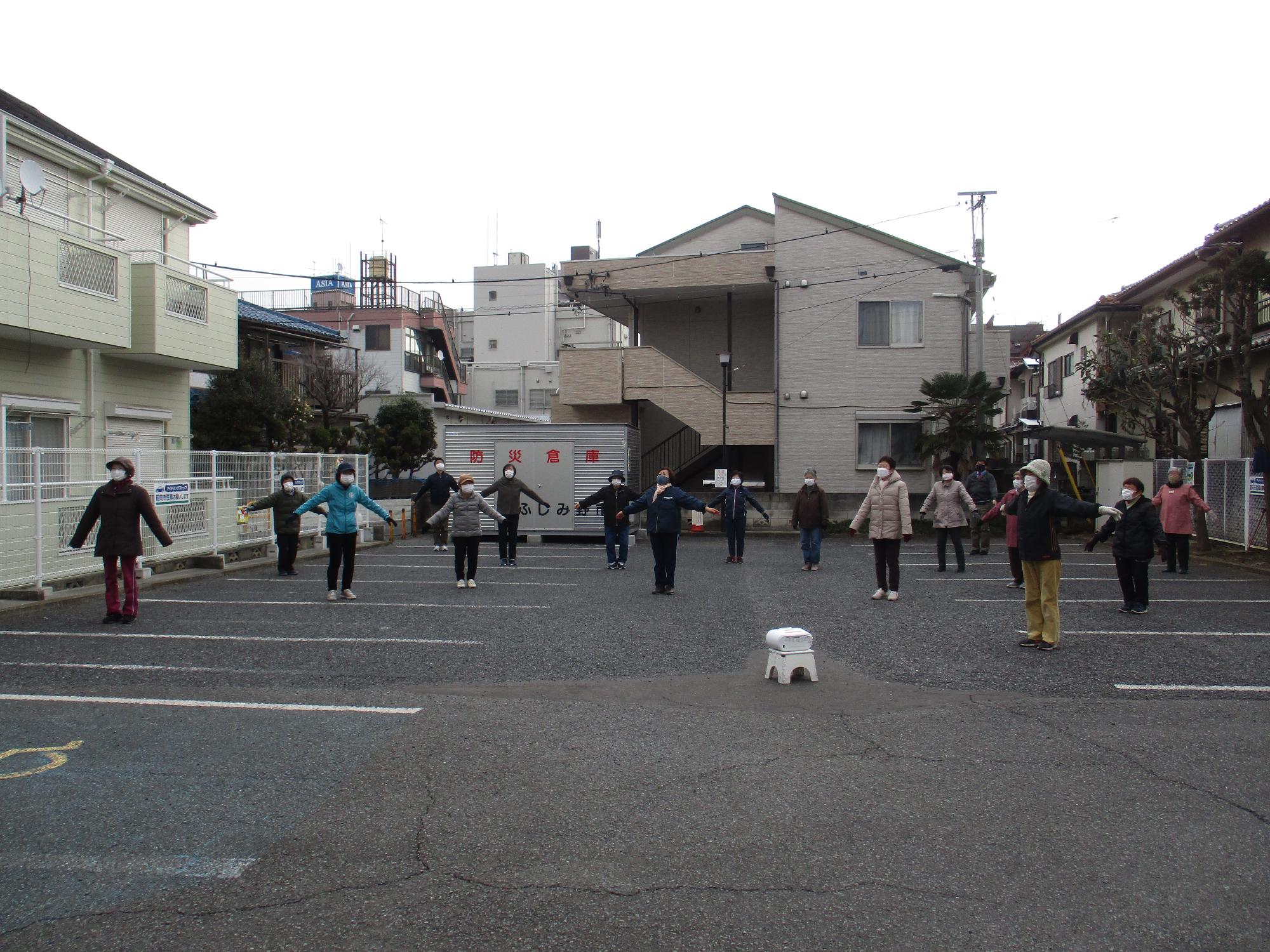 屋外でラジオ体操を行っている写真