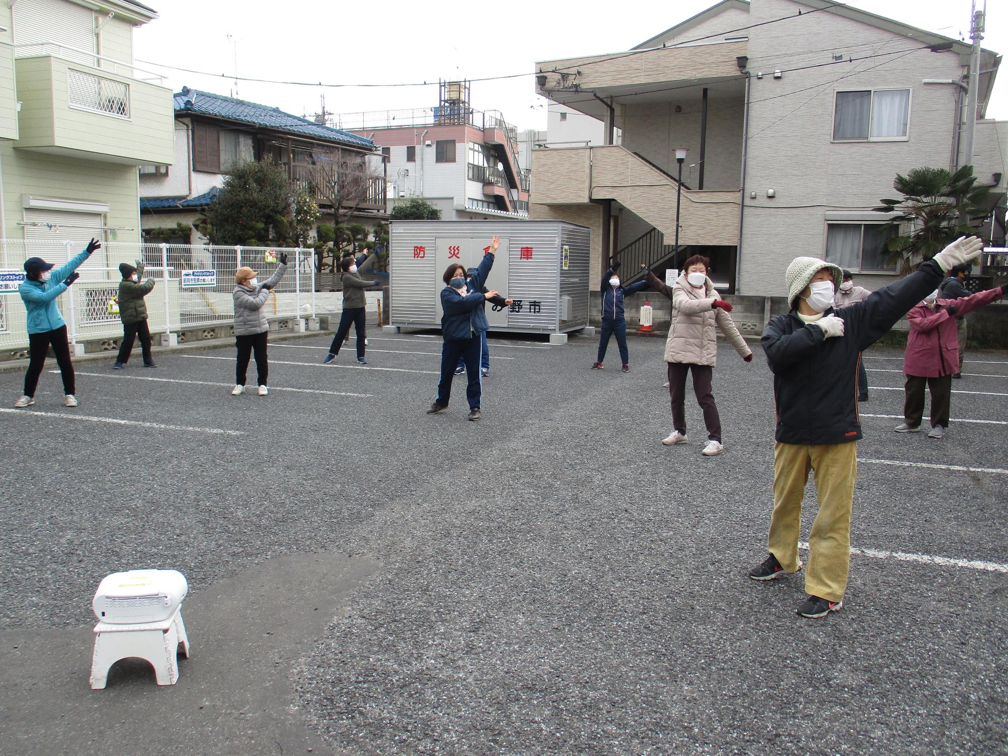 屋外でラジオ体操を行っている写真