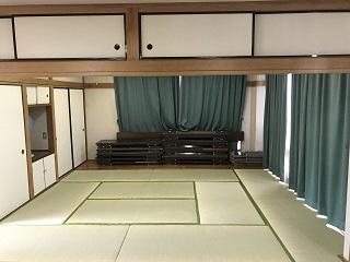 10畳の和室で、部屋の隅に会議用テーブルがつまれている様子の写真