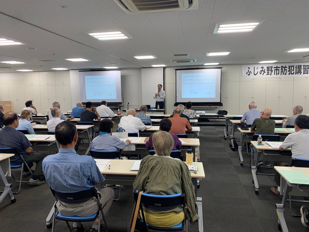 令和7年度防犯講習会で講師がスライドを使って講話しているのを多くの受講者が聞き入る様子の写真