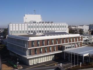 白い縁取りにレンガ色の壁が快晴の空に映える本庁舎の写真